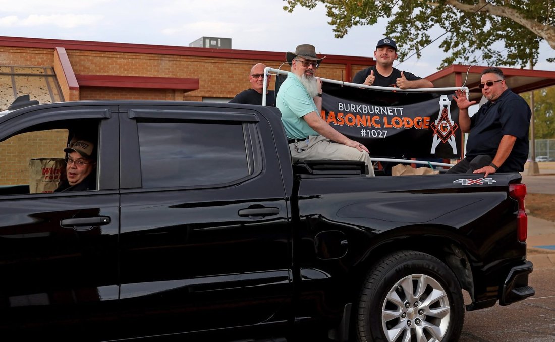 Parade participants riding in a black pickup beside the Burkburnett Masonic Lodge No. 1027 banner